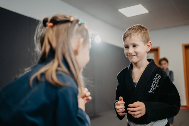 Kinder beim Luta Livre Training, konzentriert und lachend während einer Partnerübung im Trainingsraum.