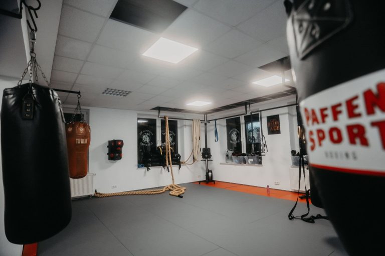 Trainingsraum der Sportschule Harrycane mit Boxsäcken, Kletterseilen und gepolsterter Matte, bereit für intensives Training.